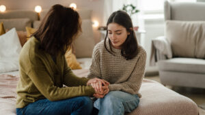 worried mom talking to young teen girl in her bedroom