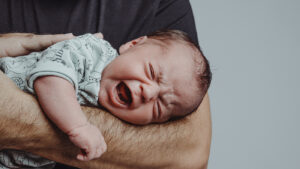 newborn crying on his father's arm