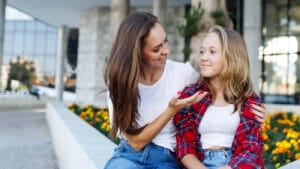 A mother sits and talks with teenage daughter.