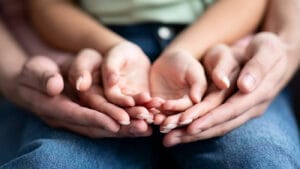 A mother cups hands around child's hands.