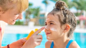 A mother applies sunscreen to child's nose.