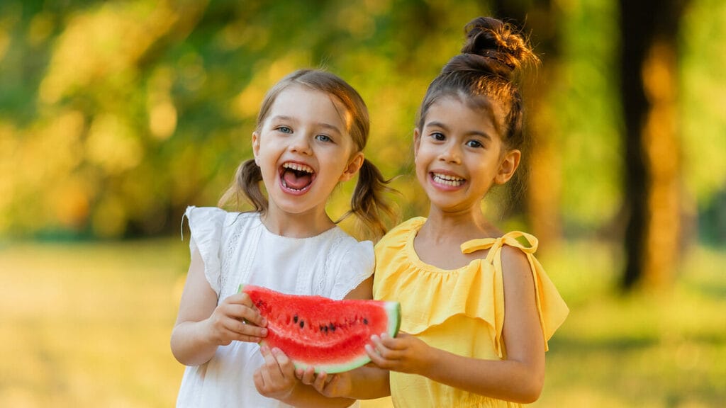 Two happy girls share watermelon.
