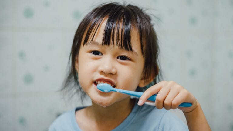 A little girl brushes her teeth.