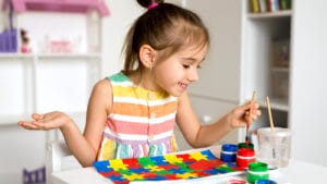 happy young girl painting a puzzle for autism awareness