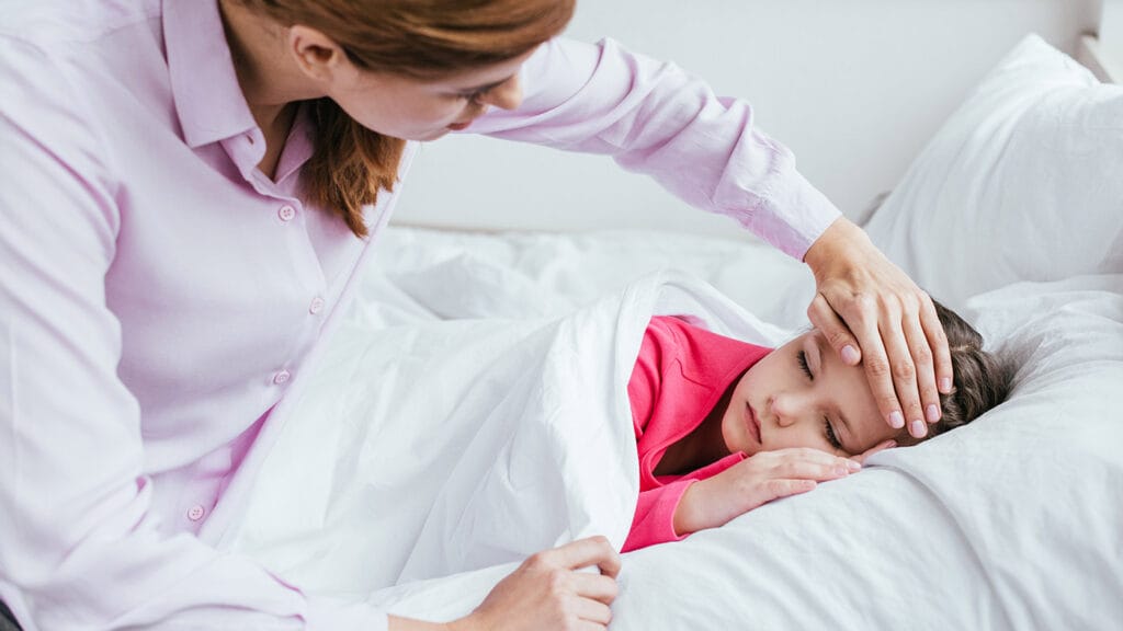 Mother checks sick child's temperature with hand.
