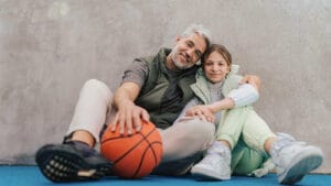 A father and daughter take a break from basketball together.