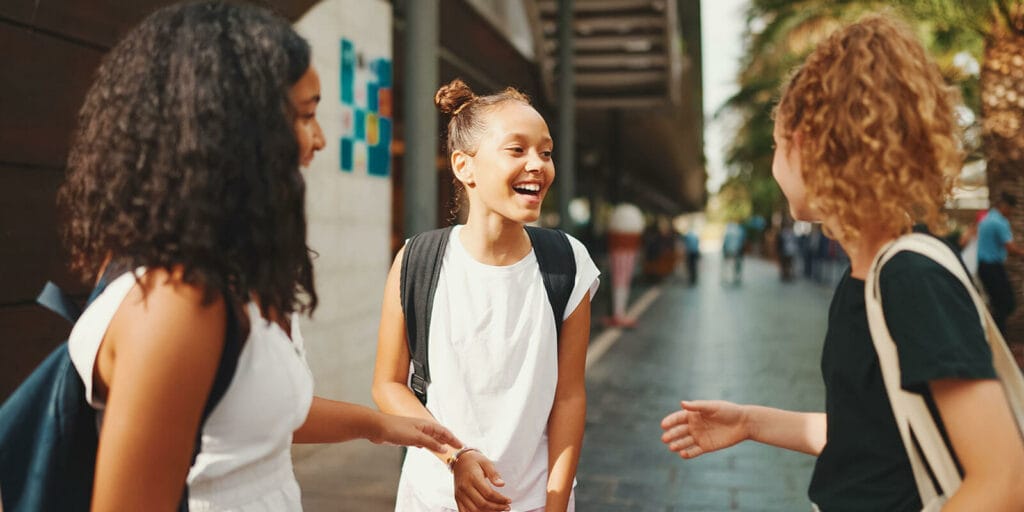 Three adolescent girls chat at school.