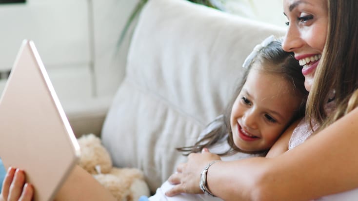 Mother and daughter smile while reviewing tablet