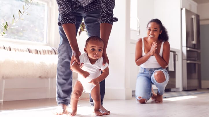 A happy mother watching husband teaching son to walk