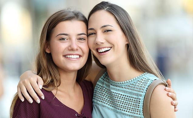 Two teens smiling and showing beautiful teeth