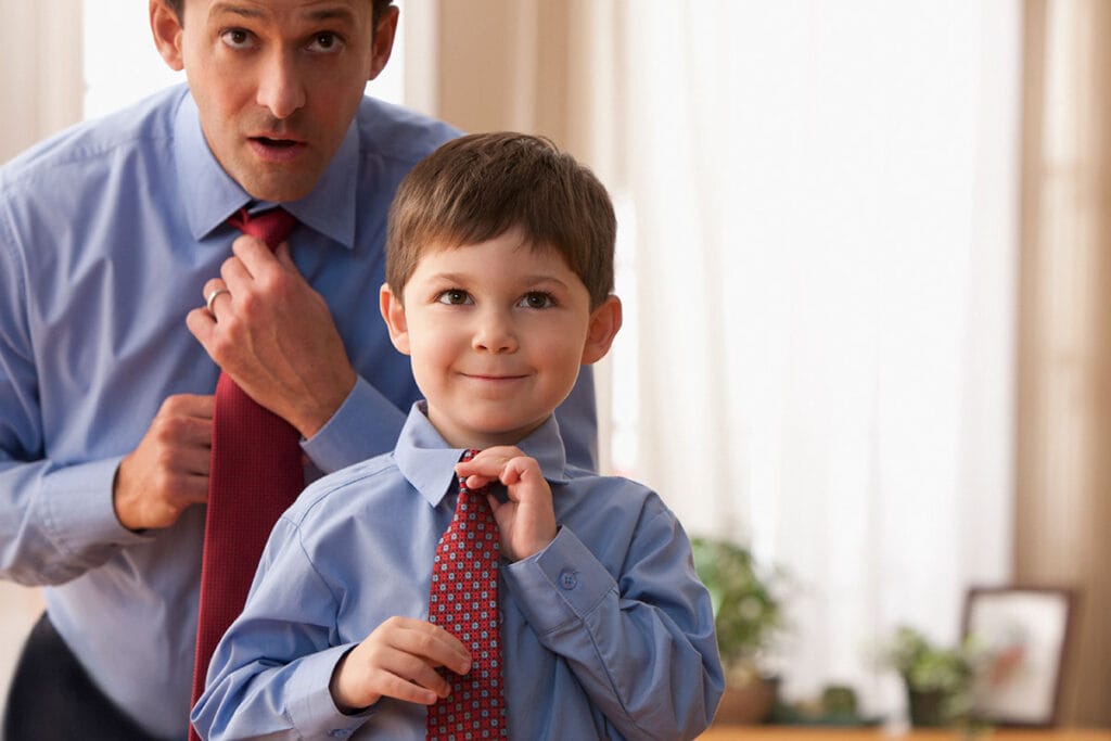 Father and son fixing ties in the mirro