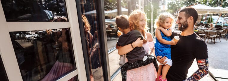 Young couple holding their kids in their arms strolling around town