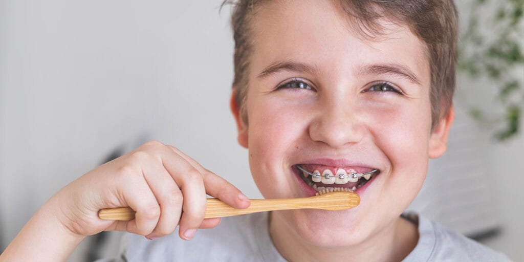 A happy teen boy brushes his teeth and braces