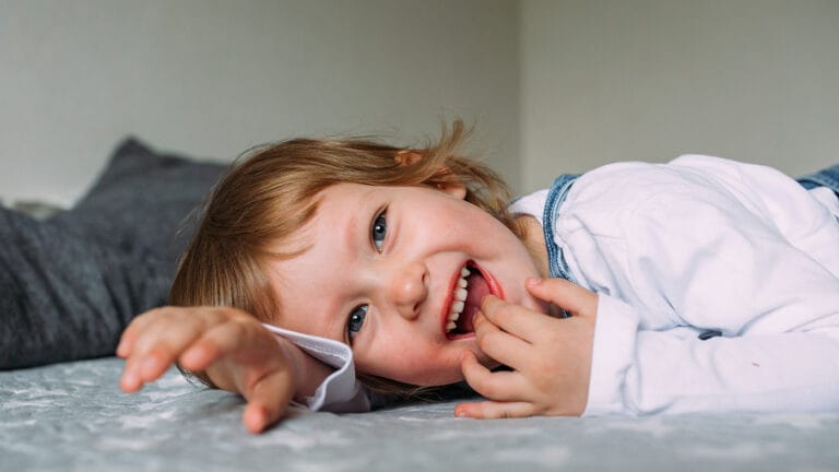 toddler laying on the best smiling.