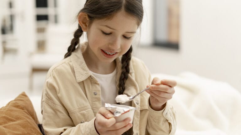 Young girl with braces eating yogurt after school