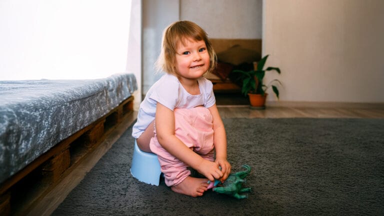 Young toddler potty training with her dinosaur toy