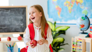 kindergartener in a school classroom holding an apple