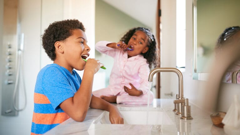 Siblings brushing their teeth together in the bathroom