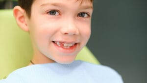 young boy sitting in an orthodontic chair after treatment