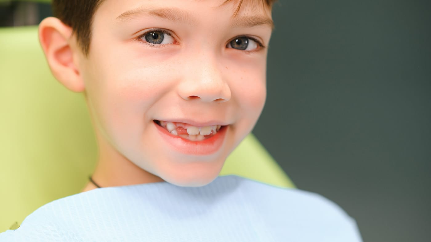 young boy sitting in an orthodontic chair after treatment
