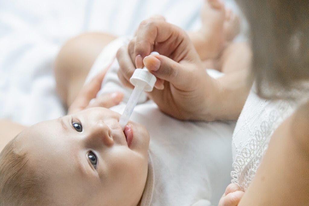 Mother using a dropper to medicate her infant
