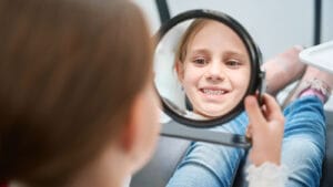 tween girl smiling in a mirror at a dental appointment