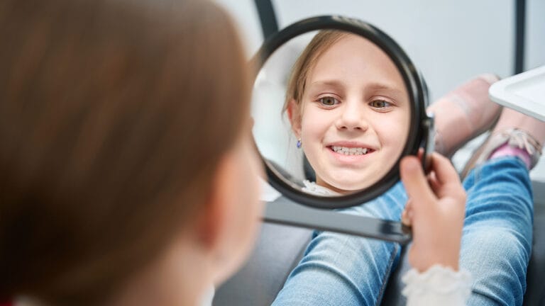 tween girl smiling in a mirror at a dental appointment