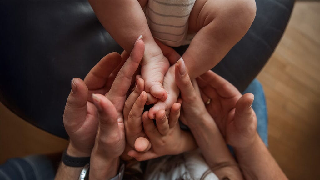 Parents lovingly holding onto their newborn's feet