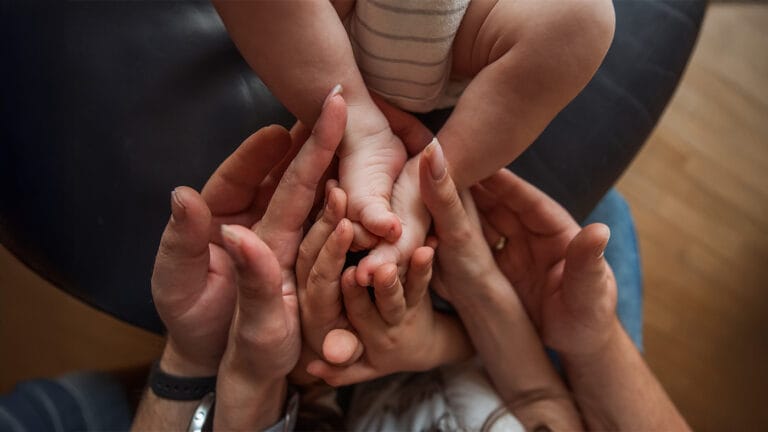 Parents lovingly holding onto their newborn's feet