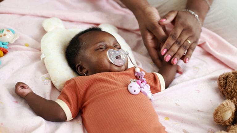 Young newborn sleeping while being soothed by mother