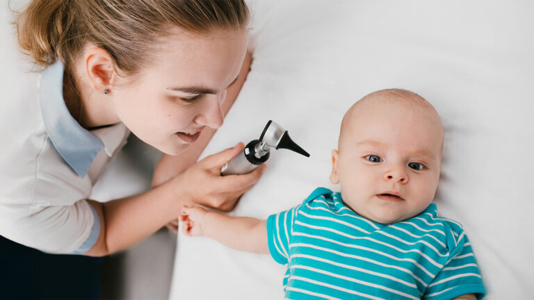 Pediatrician looking at baby's ear