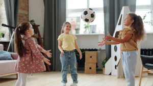 Three young girls playing catch inside
