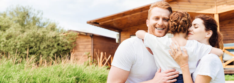 A couple holding up their daughter and embracing her between their arms