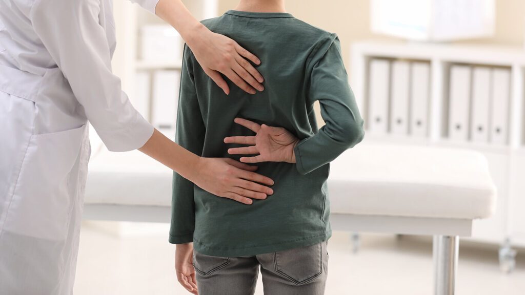 Young boy having his back examined by a doctor