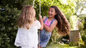 two girls swinging on a tire swing outside