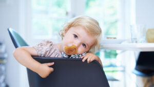 Toddler girl with a binky in a chair