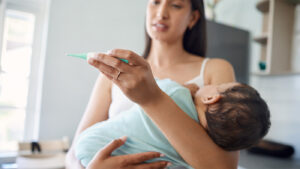 A mother holding her infant in her arms to check their temperature
