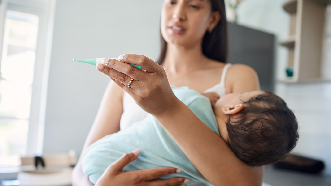 A mother holding her infant in her arms to check their temperature