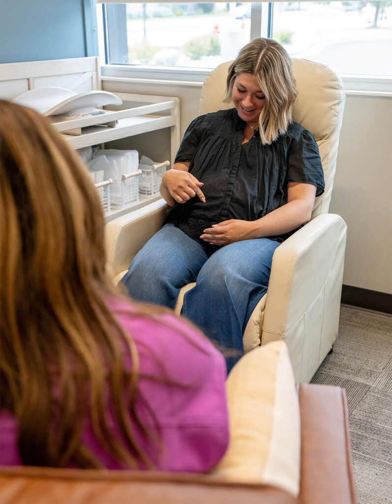 Happy pregnant mom visits with an IBCLC lactation consultant