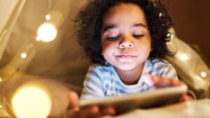 Young girl on a phone under her covers on her bed