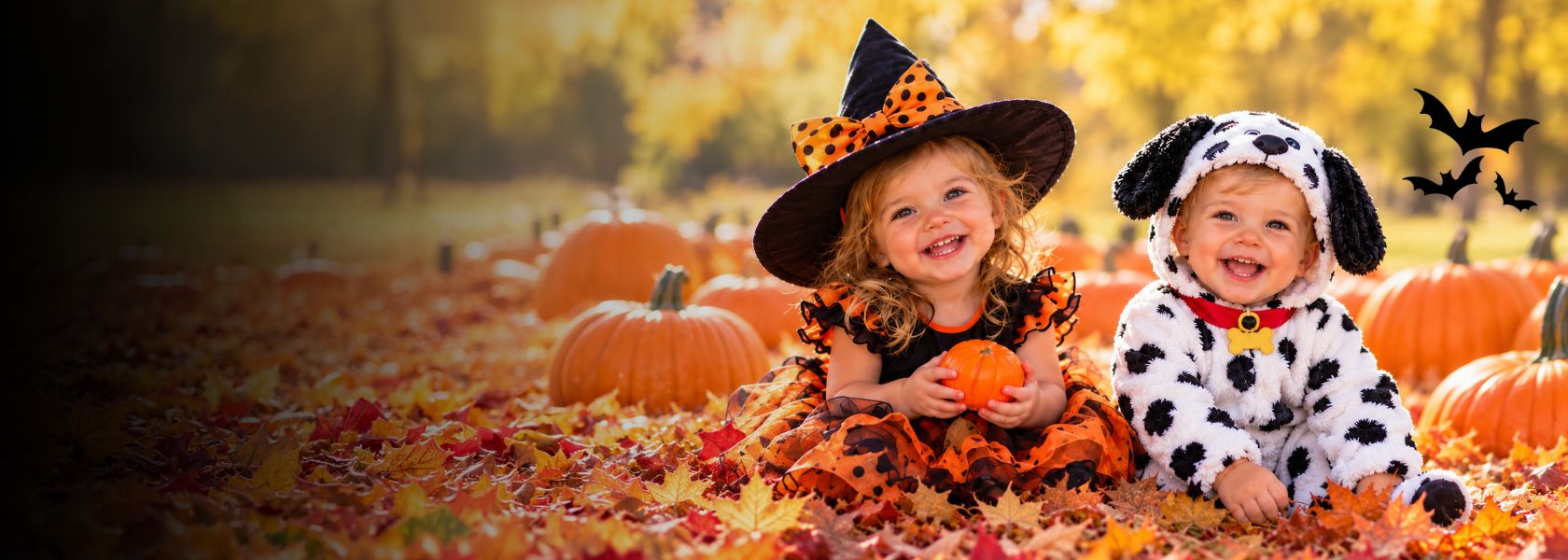 two young kids in a pumpkin patch dressed as a witch and dalmatian