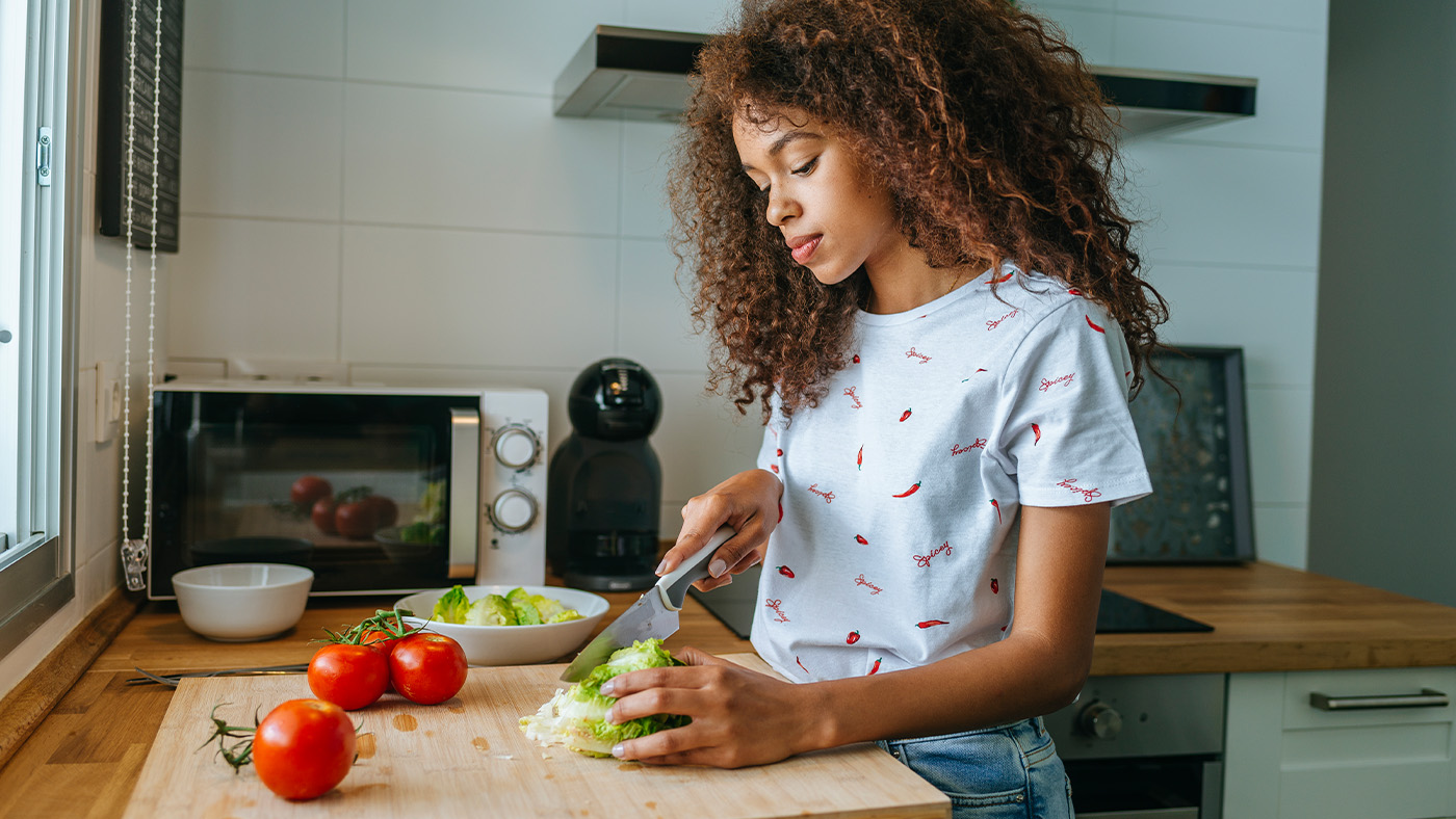 Young woman cutting vegetables on a cutting board
