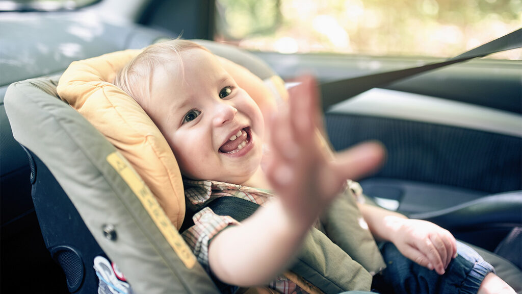 Baby in a car seat reaching out to the camera