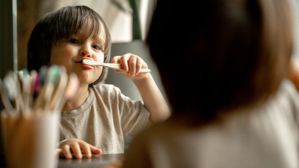 Young child brushing teeth in the mirror