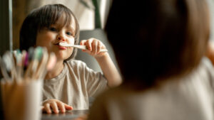 Young child brushing teeth in the mirror